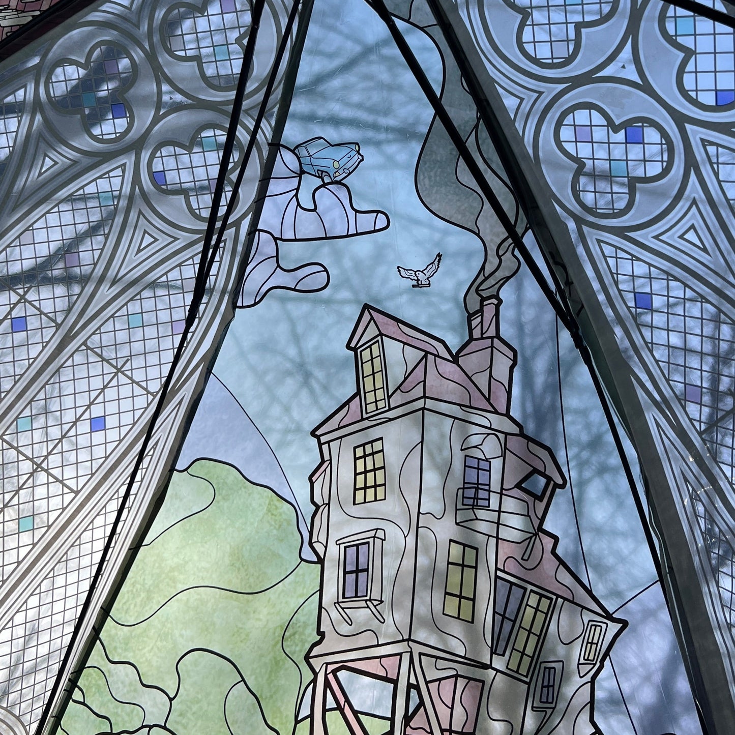 Stylized illustration of a house with a dragon and bird, framed by decorative glass patterns.