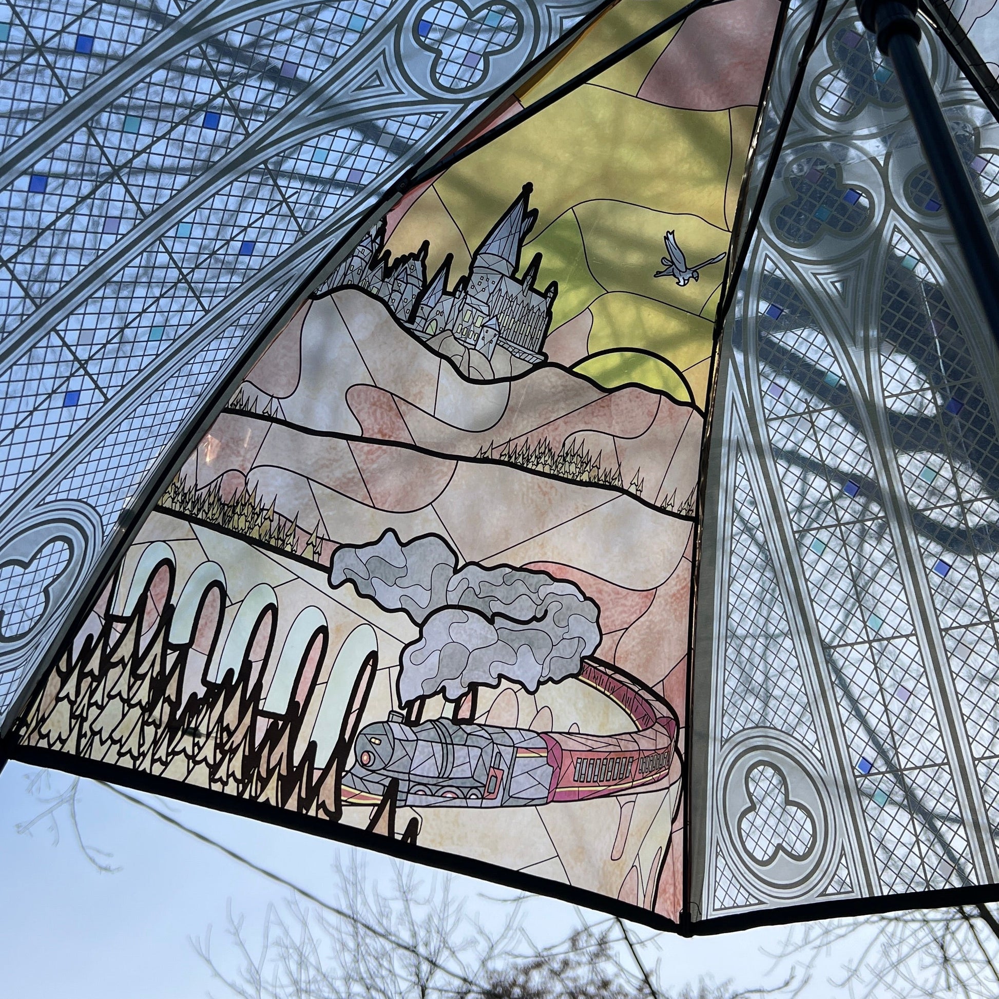 Wizard-inspired stained glass canopy umbrella featuring illustrated panels of a magical castle, whimsical crooked house, enchanted willow tree, grand candlelit dining hall, and vintage steam train.