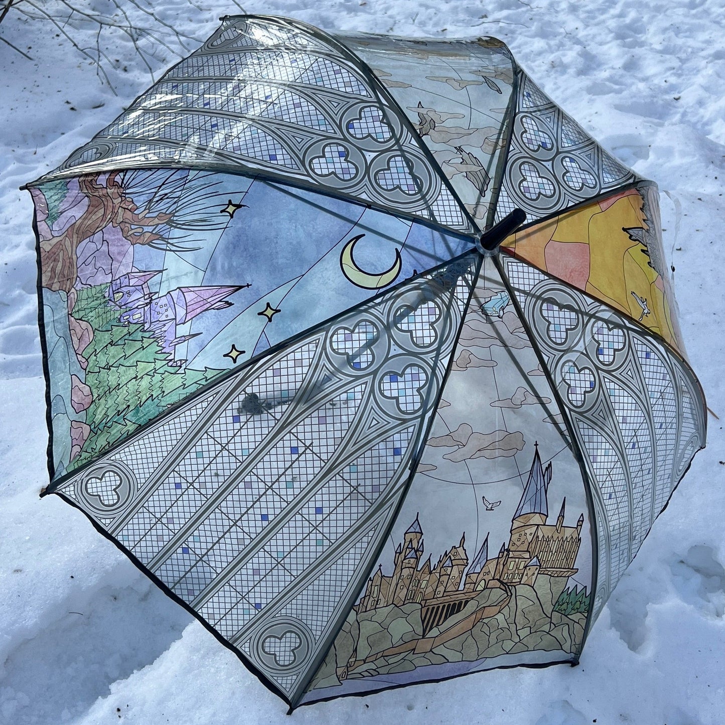 Wizard-inspired stained glass canopy umbrella featuring illustrated panels of a magical castle, whimsical crooked house, enchanted willow tree, grand candlelit dining hall, and vintage steam train.