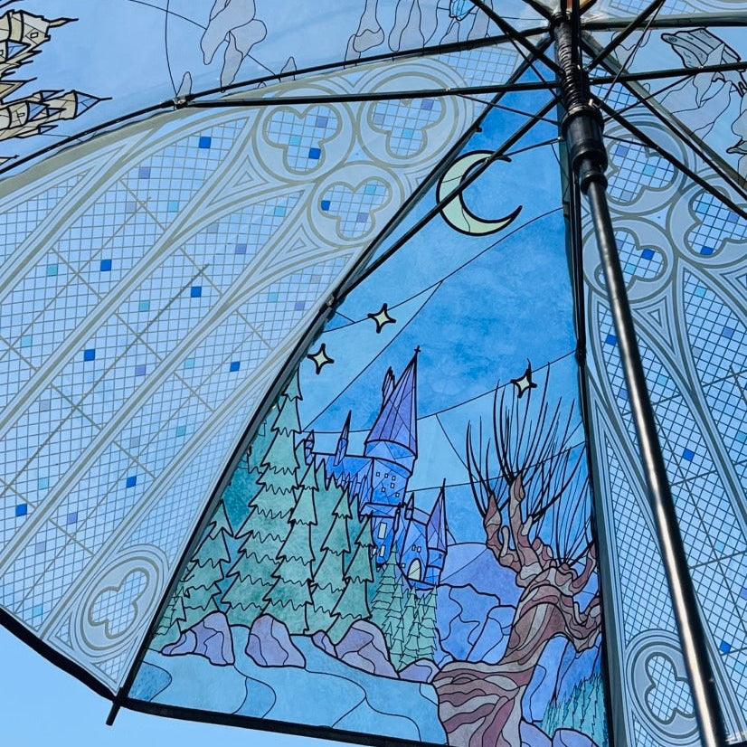 Umbrella with stained glass design featuring a castle and nature elements.